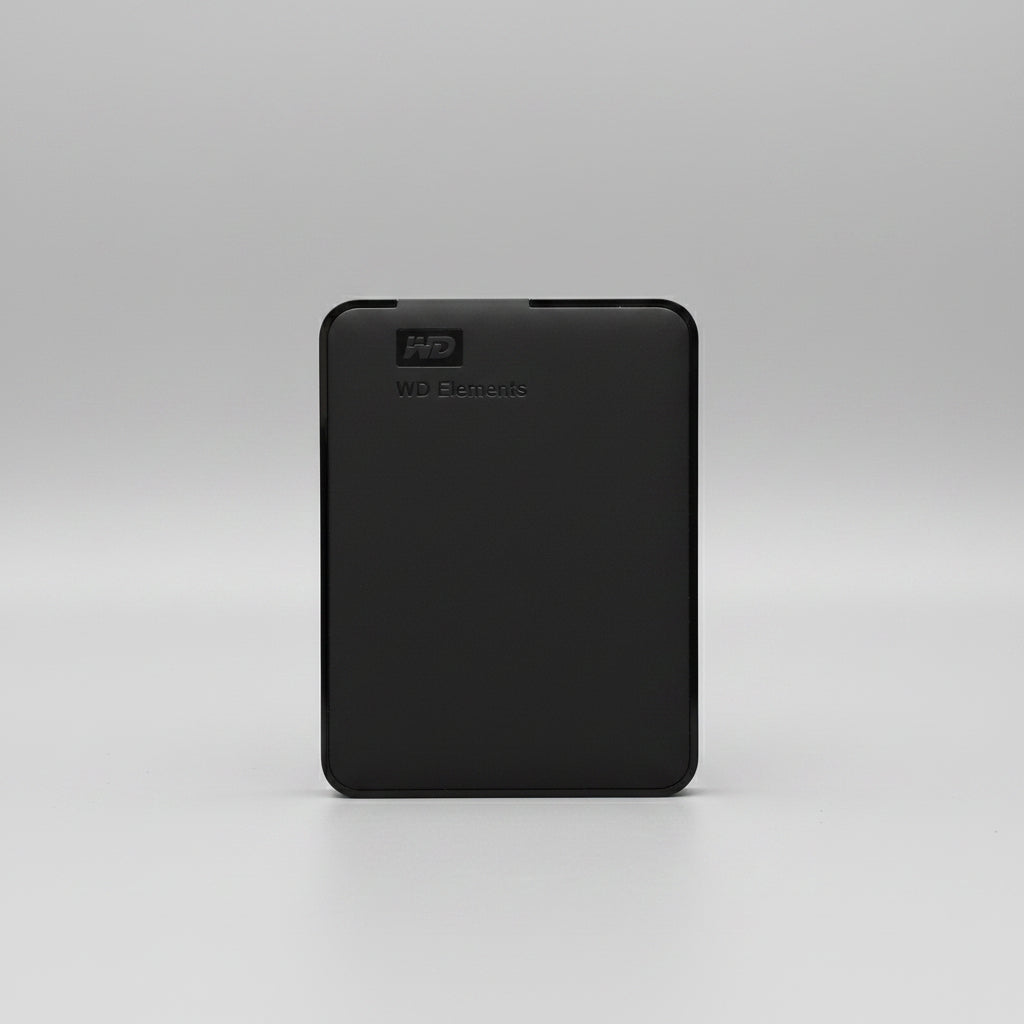 A black Western Digital WD Elements portable external hard drive standing upright on a wooden tabletop against a white paneled wall.