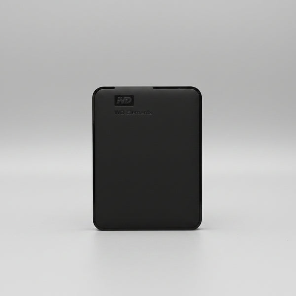 A black Western Digital WD Elements portable external hard drive standing upright on a wooden tabletop against a white paneled wall.